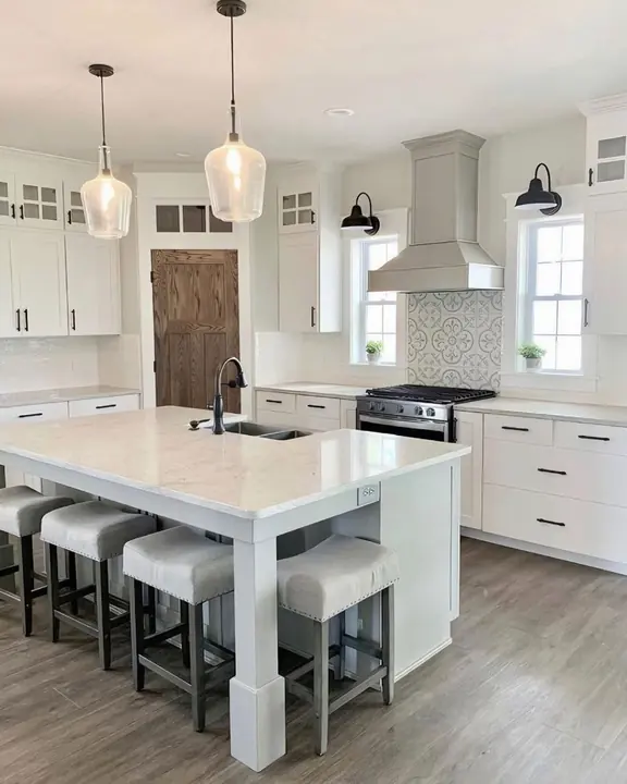 White farmhouse kitchen with island sink, patterned backsplash and wood pantry door