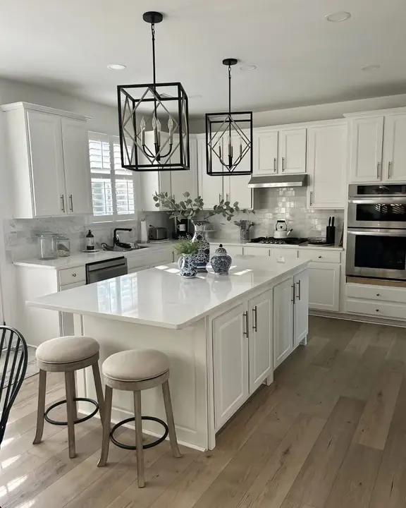 White kitchen with quartz island and black lantern pendants